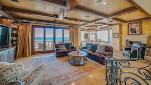 A spacious living room with a large window overlooking the sea, furnished with leather sofas and a fireplace. - Beach Front Executive Home (Long Beach)