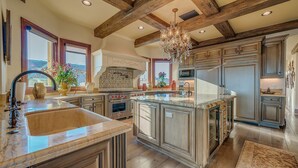 A spacious kitchen with a large island, wooden beams on the ceiling, and a chandelier. - Beach Front Executive Home (Long Beach)