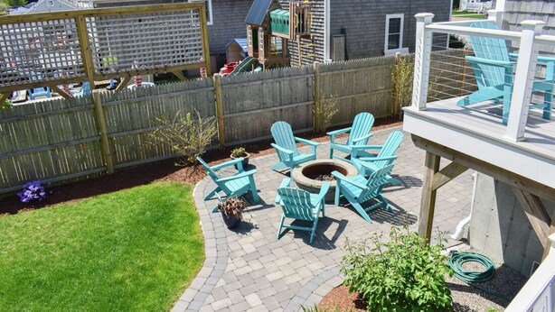 A backyard patio with a fire pit, outdoor seating, and a wooden deck. - Three bedroom home- quick stroll to Nantucket Sound Beaches (Dennis Port)