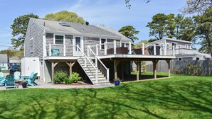 A two-story house with a covered deck and a staircase leading to the upper level. - Three bedroom home- quick stroll to Nantucket Sound Beaches (Dennis Port)