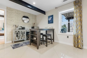 A modern kitchen with a brick wall, a round mirror, a coffee machine, and a window with a view.