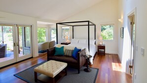 A modern bedroom with a four-poster bed, a sofa, and a bench.
