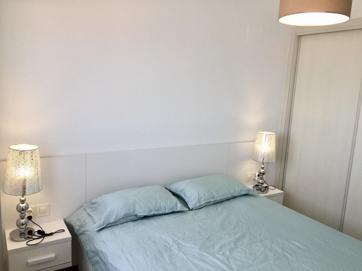 A bedroom with a bed, two bedside lamps, and a nightstand.