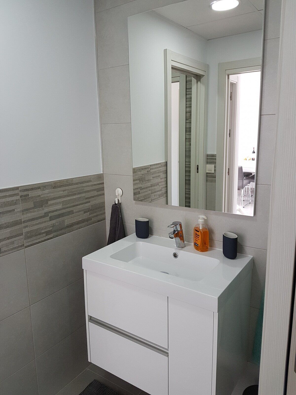 A bathroom with a white sink, a mirror, and a towel rack.