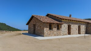Un edificio de piedra con techo de tejas, un pequeño porche y una vista despejada del paisaje circundante.
