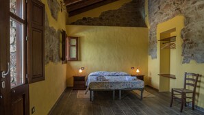 Un dormitorio con cama, dos mesitas de noche, una silla, un armario y una ventana.