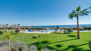 Un resort con piscina, palmeras y vista al mar.