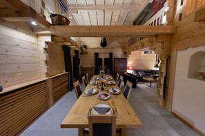 Un comedor de madera con una mesa larga dispuesta para ocho personas, rodeada de sillas.