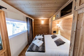 Ein Holzhüttenraum mit einem Bett, einem Fenster und einem kleinen Tisch mit Handtüchern.