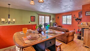 Un comedor con una mesa de madera preparada para cuatro personas, un sofá y una chimenea.