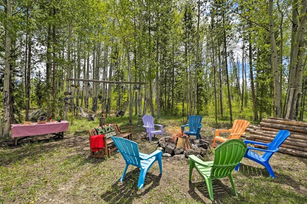 An outdoor seating area with colorful Adirondack chairs, a fire pit, and a picnic table.