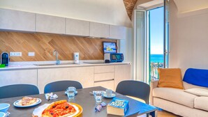 Een moderne keuken met een spatwand van hout in visgraatmotief, een inbouwoven en een raam met uitzicht op zee.
