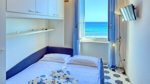 Een slaapkamer met een bed, een raam met uitzicht op zee en een plafond met zichtbare balken.