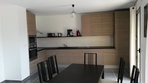 A modern kitchen with a dining table, chairs, and a chandelier.