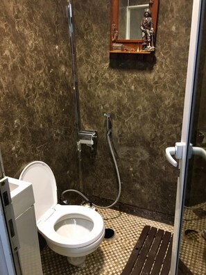 A bathroom with a toilet, shower, and a mirror with a statue. - The HouseBoat Mermaid (Dubai)