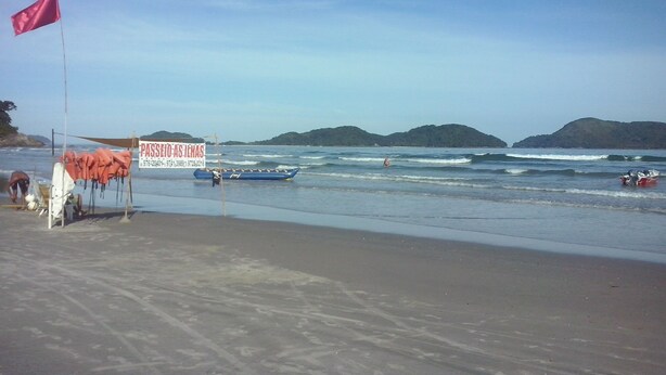 Ein Strand mit einem Schild, einer Flagge und einem Boot im Wasser.