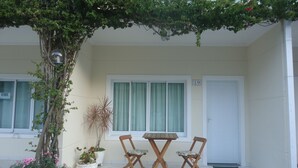 Eine kleine Terrasse mit Tisch und zwei Stühlen, einem Blumentopf und einer Tür mit der Nummer 19.