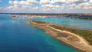 Vista aérea de una zona costera con aguas azul turquesa, playas de arena y un paisaje urbano distante.