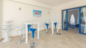 Una habitación moderna con taburetes blancos y azules, un lavabo pedestal blanco y un cuadro de un corazón en la pared.