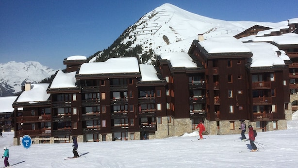 A ski resort with a mountain backdrop, featuring multi-story buildings with balconies and ski slopes in the foreground. - Studio, at the foot of the Belle Plagne slopes, sleeps 4, wifi included. (La Plagne Tarentaise)