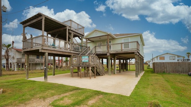 A beachfront property with a wooden deck and a 'For Rent' sign.
