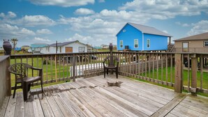 A wooden deck with a view of a blue house and other buildings in the background.