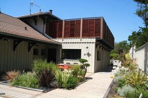 A modern house with a sloped roof, a wooden deck, and a garden with various plants. - High standard Villa, heated Pool +aircon A0335 (Lège-Cap-Ferret)