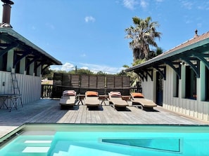 Un área de piscina con sillones de descanso y una terraza de madera.