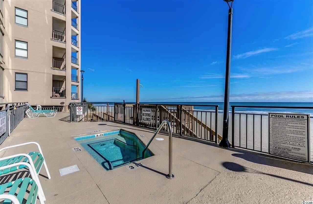 Un espace piscine comprenant une petite piscine, des chaises longues et un panneau indiquant qu’il est interdit de plonger.