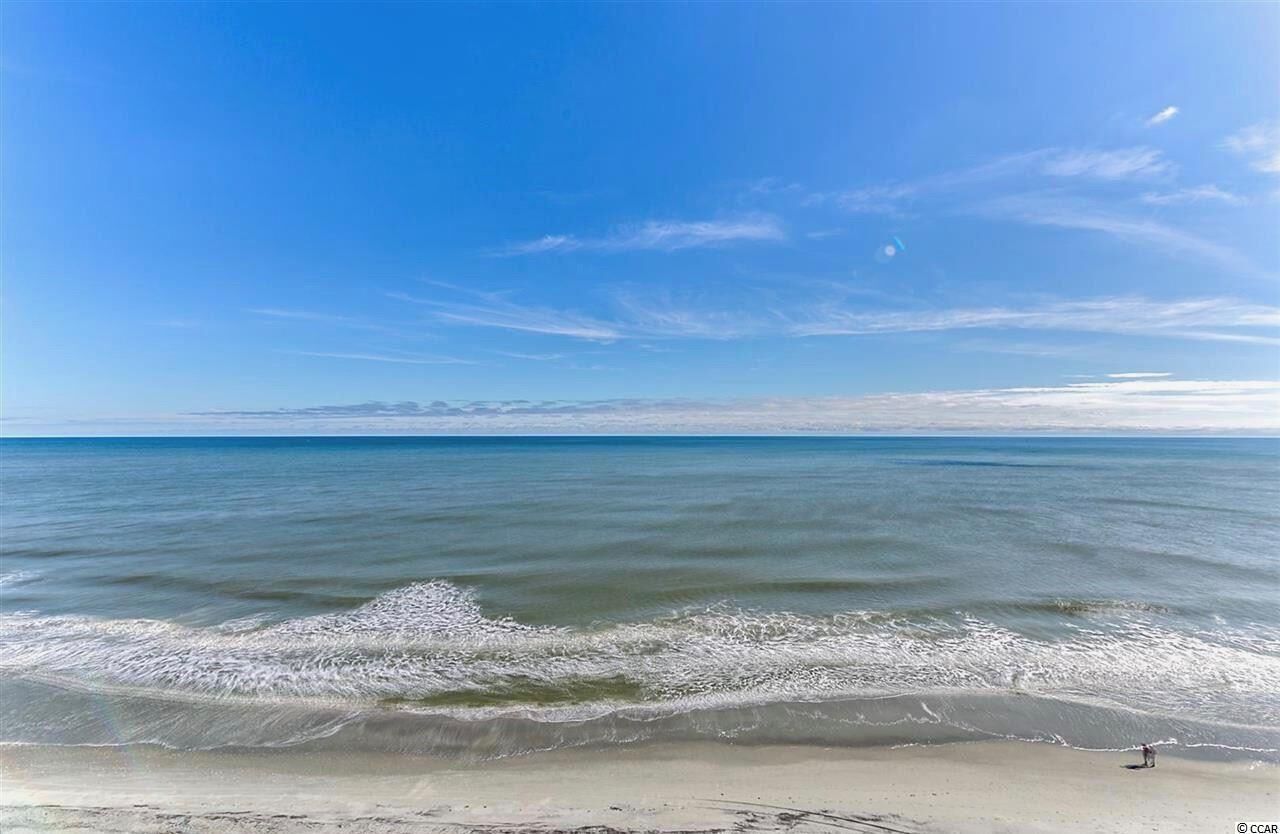 A beach with calm waves and a clear sky.