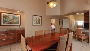 A spacious dining area with a large wooden table, wicker chairs, and a hanging light fixture. - 7 Days / 6 Nights Gateaway (Kissimmee)