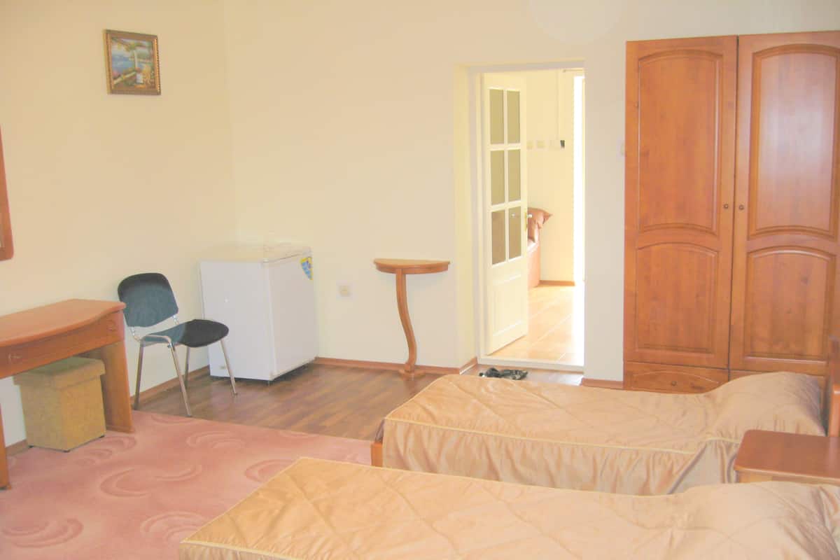 Un dormitorio con dos camas, un escritorio, una silla, una mesita y un armario.