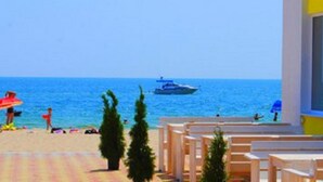 A beach view with a building, a boat, and people. - Adam & Eva (Zatoka)