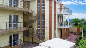 A multi-story residential building with balconies, a central staircase, and a covered outdoor area with tables and chairs. - Adam & Eva (Zatoka)