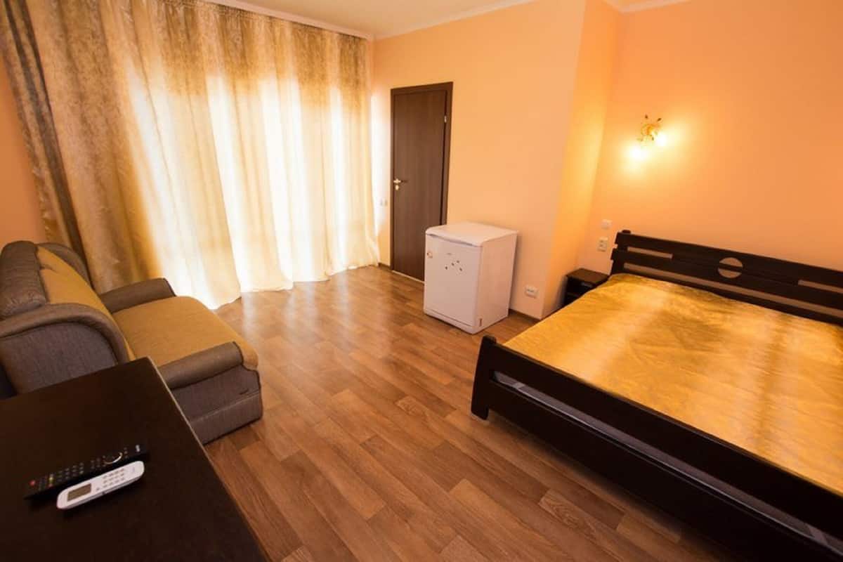 Habitación de hotel con una cama, un sofá, una mesita con un control remoto, un calentador y una puerta.