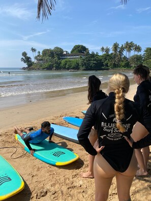A beach with surfboards and people preparing to surf. - Residence Kuruniyavilla (Unawatuna)
