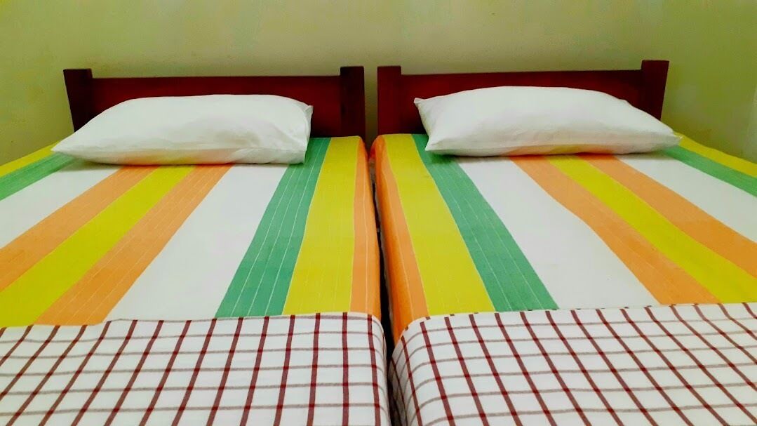 Une chambre avec deux lits, chacun recouvert d’une couvre-lit à rayures et agrémenté d’oreillers blancs.