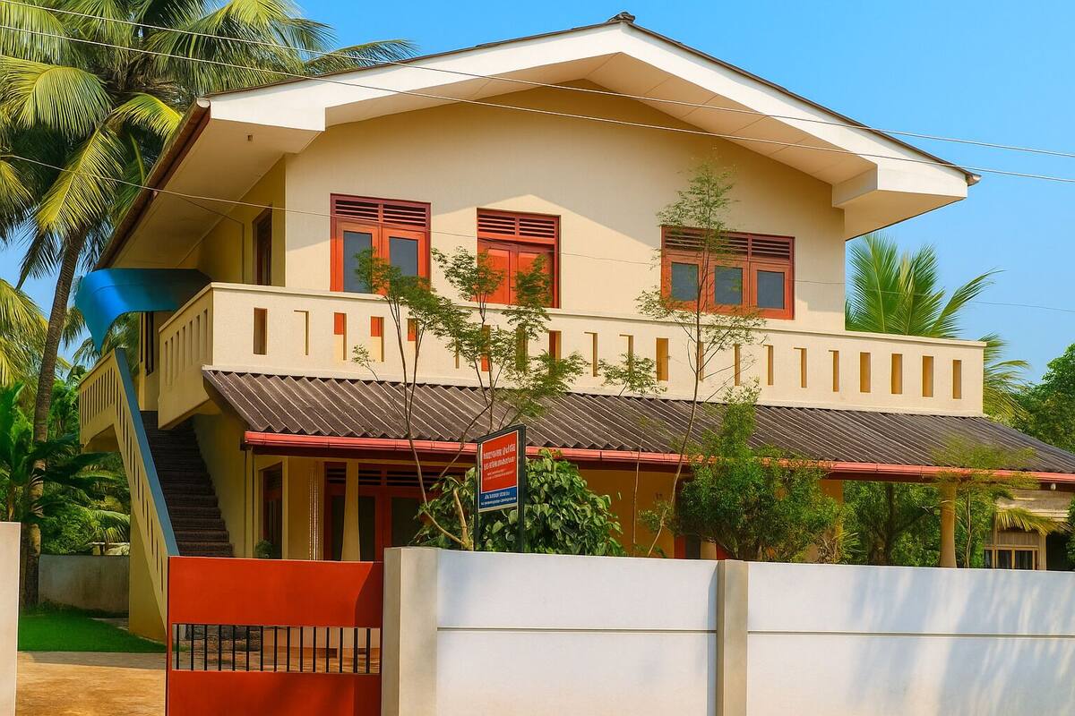 A two-story house with a balcony, a staircase, and a red gate.