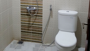 Une salle de bain avec une douche, des toilettes et un mur décoré de motifs.