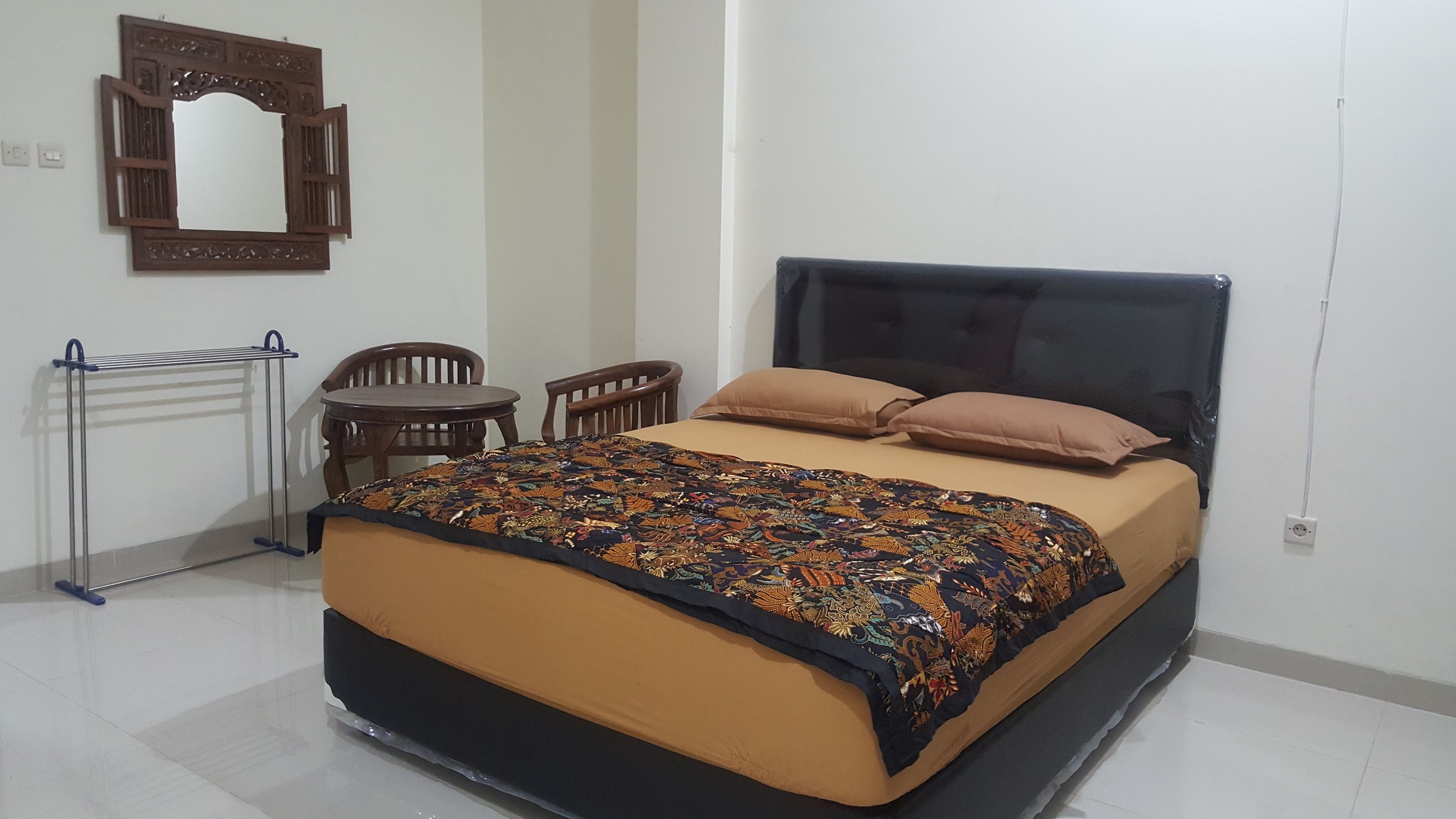 A bedroom with a bed, two chairs, a small table, and a radiator.