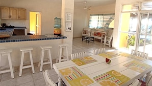 A kitchen with a blue countertop, white stools, and a dining table with a fruit pattern. - La Casa de la Playa (Cuyutlan)