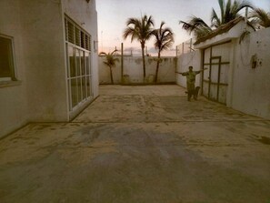 A courtyard with a concrete floor, white walls, and palm trees.