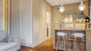 Eine moderne Küche mit Holzboden, einer integrierten Bar und zwei Barhocker.