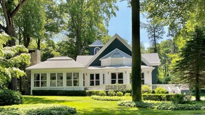 A large, two-story house with a prominent gable roof, surrounded by lush greenery and trees. - 1800's Church, Restored And Converted To A Designers Private Beach Retreat (Coloma)