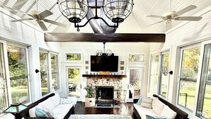 A spacious living room with a fireplace, large windows, and a ceiling fan. - 1800's Church, Restored And Converted To A Designers Private Beach Retreat (Coloma)
