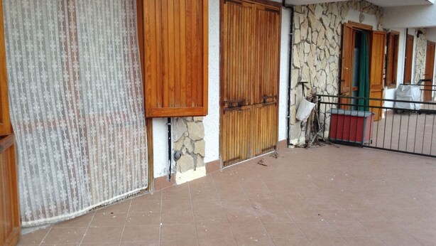 A building with a tiled patio, wooden doors, and a stone wall. - MOUNTAIN HOUSE PESCASSEROLI (pescasseroli)