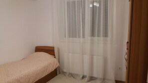 Cozy retreat with a single bed and a window with sheer curtains.