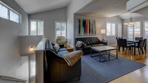 A modern living room with a sofa, coffee table, and dining area.