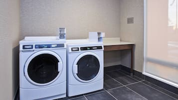 A laundry area with two front-loading washing machines and a small table.