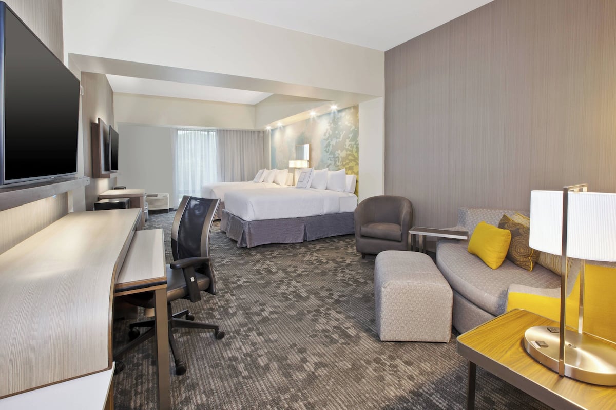 Een hotelkamer met een groot bed, een bureau met stoel, een bank met lamp en een televisie.